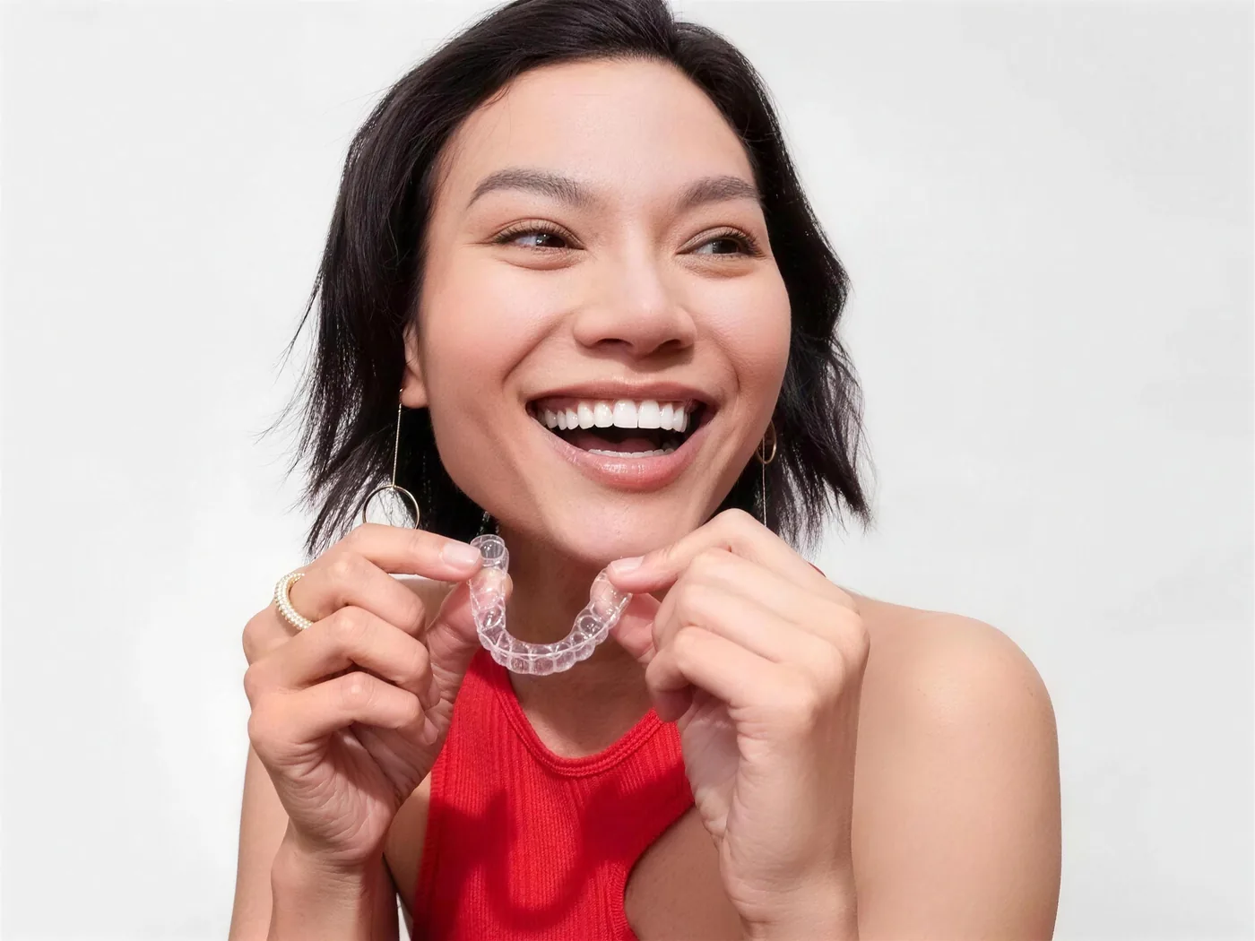 Smiling patient holding a clear aligner tray at Green Dentistry: Root and Restore in Alexandria, VA